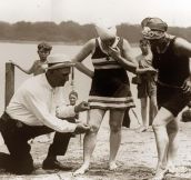 An beach official measures bathing suits to ensure they aren’t too short 1920s