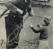 An East German soldier ignores orders to let no one pass and helps a boy, who was found on the opposite side from his family, cross the newly formed ‘Berlin Wall’- 1961
