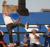 65 year old Man Catching a homerun ball in front of the railings in the Wrigley Field Bleachers.