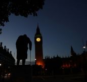 Dawn breaks behind the Houses of Parliament and the statue of Winston Churchill in Westminster, London